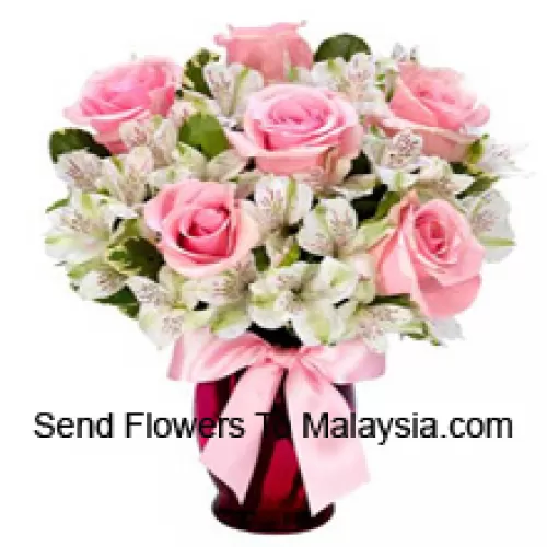 Kauniisti asetellut vaaleanpunaiset ruusut ja valkoiset alstroemeriat lasimaljakossa