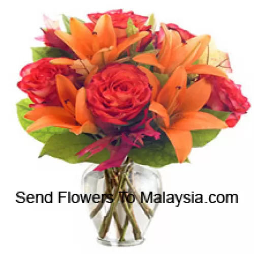 Оранжевые лилии и оранжевые розы с сезонными наполнителями красиво оформлены в стеклянной вазе